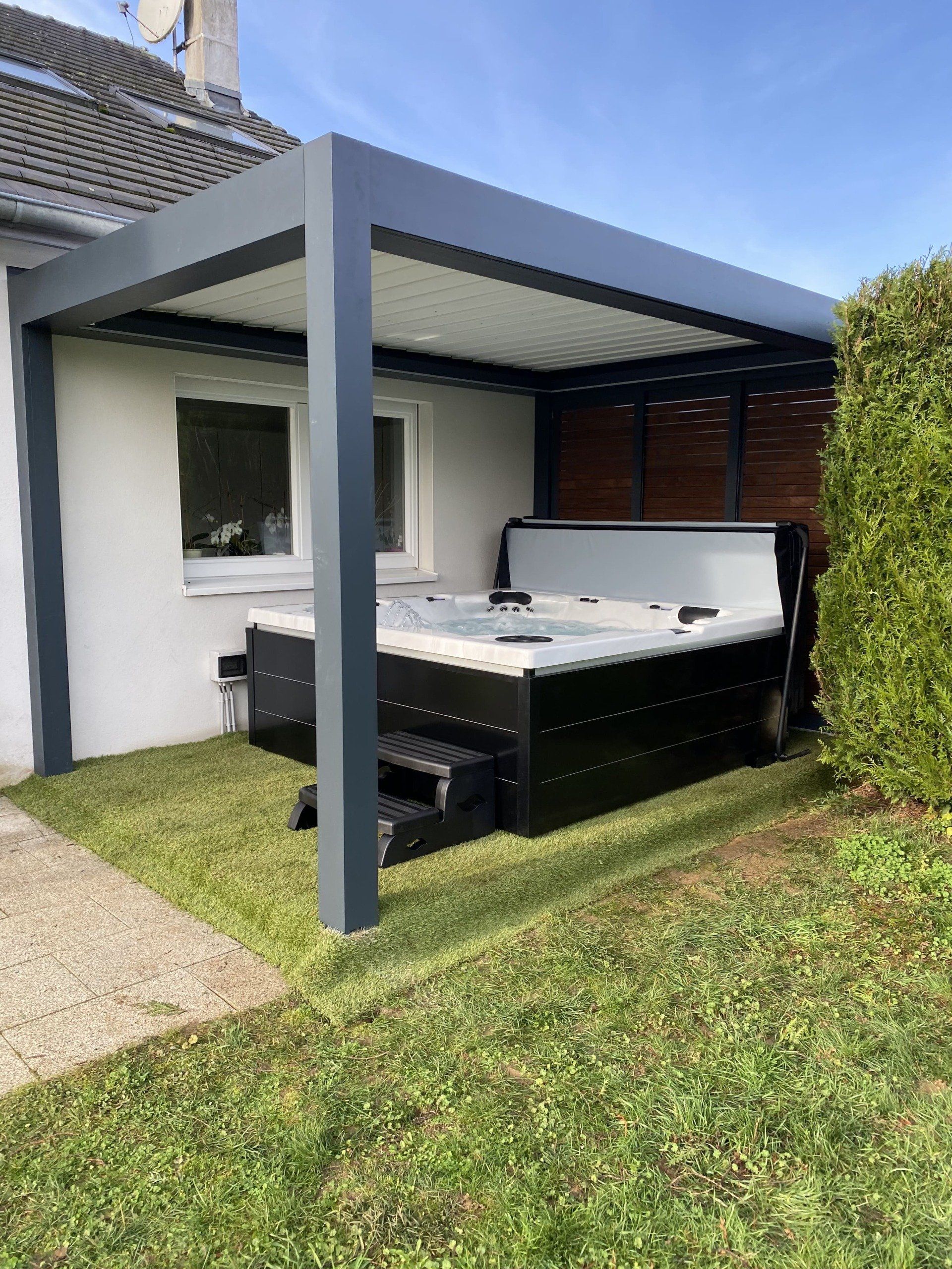 Un bain à remous se trouve sous une pergola dans l'arrière-cour d'une maison.
