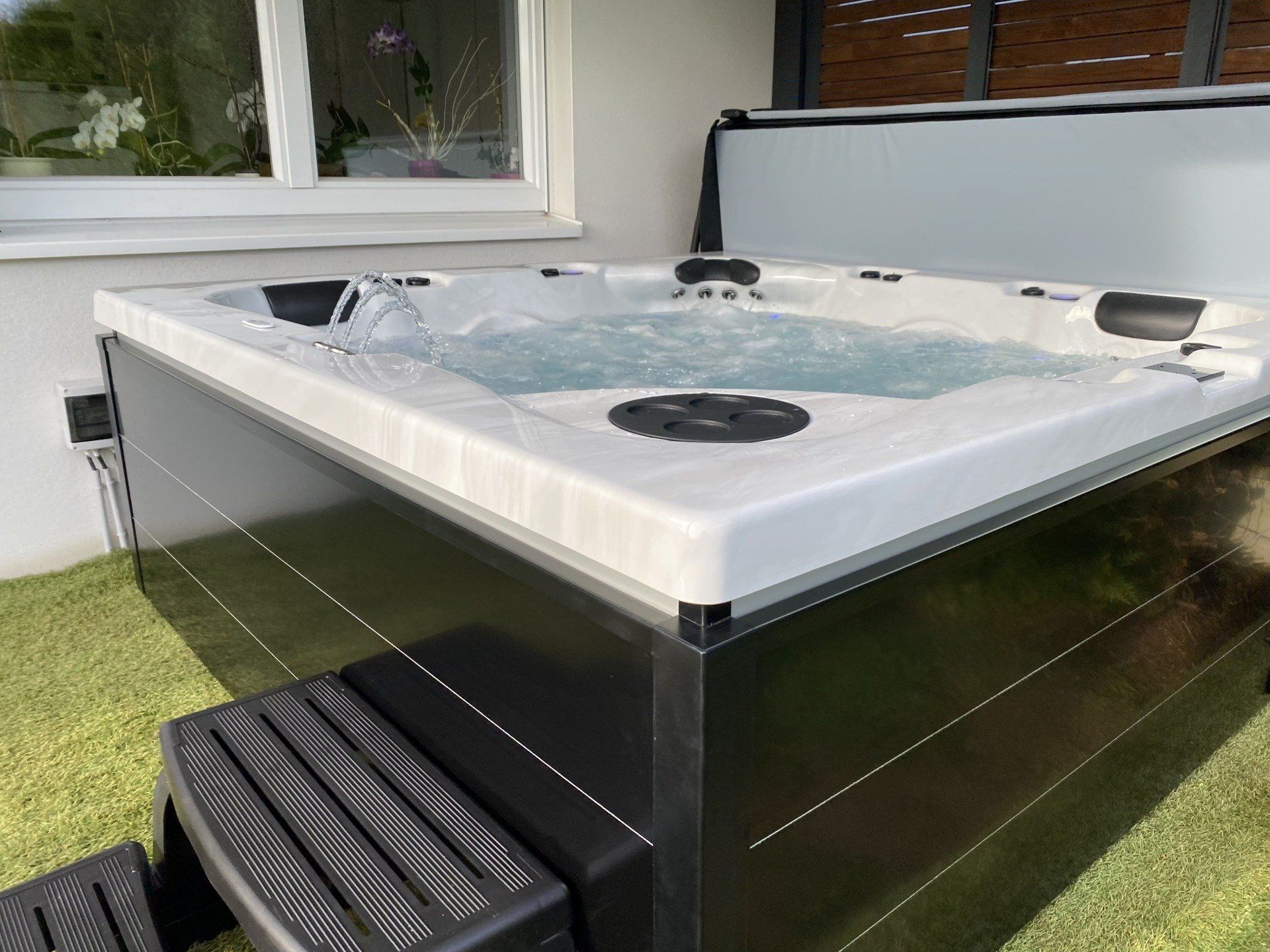 Un jacuzzi blanc et noir est posé sur une pelouse verte luxuriante.