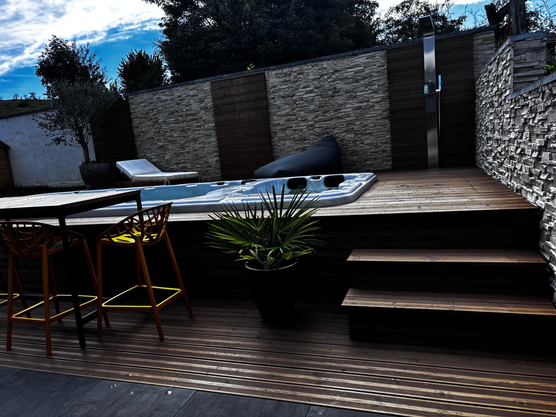 Un patio avec un bain à remous et des escaliers qui y mènent