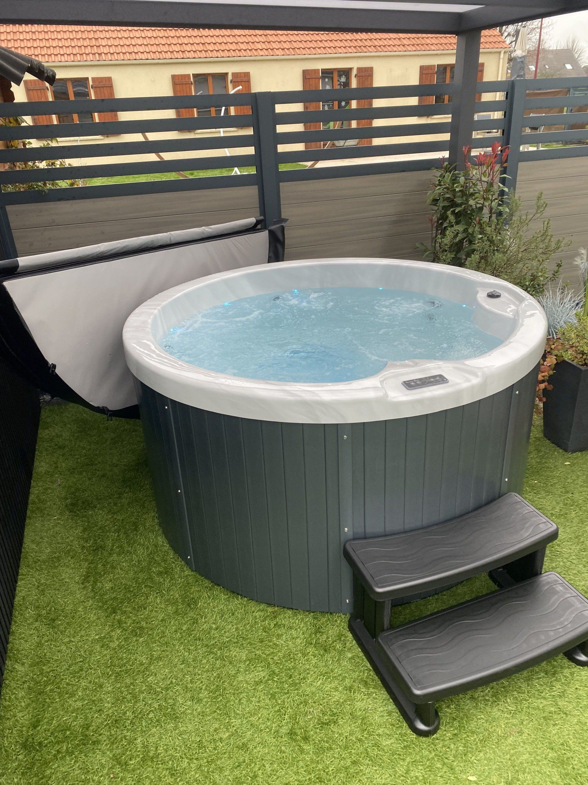 Un bain à remous rond est posé sur une pelouse verte luxuriante.
