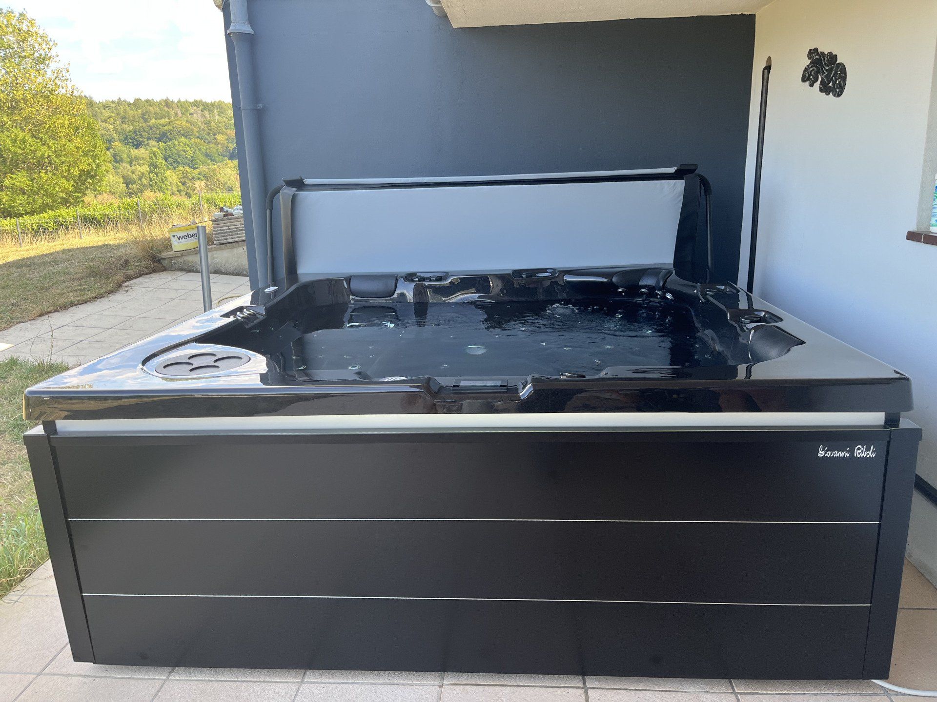 Un jacuzzi noir avec le couvercle ouvert sur une terrasse