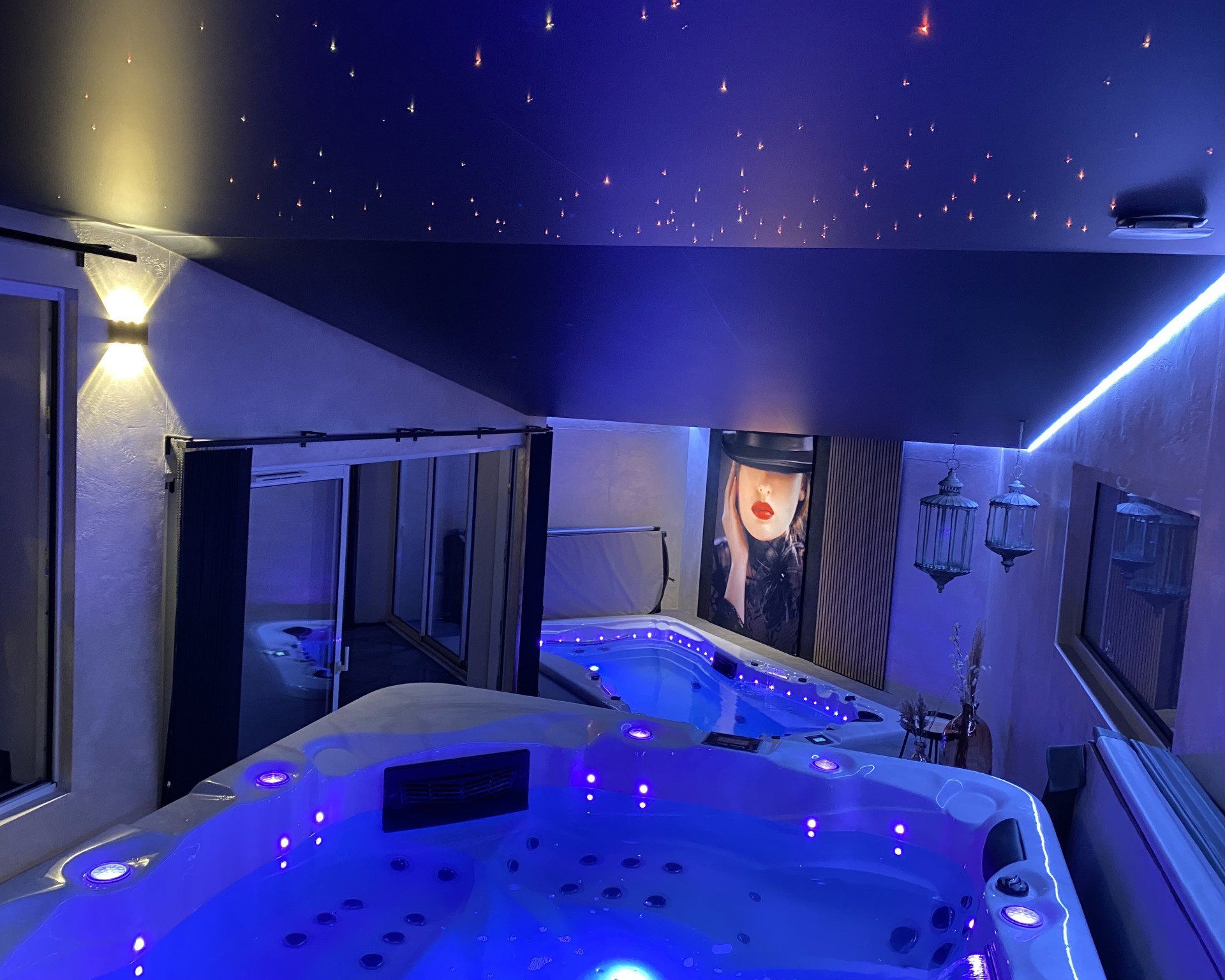 Un grand bain à remous est installé sous un ciel étoilé dans une pièce.