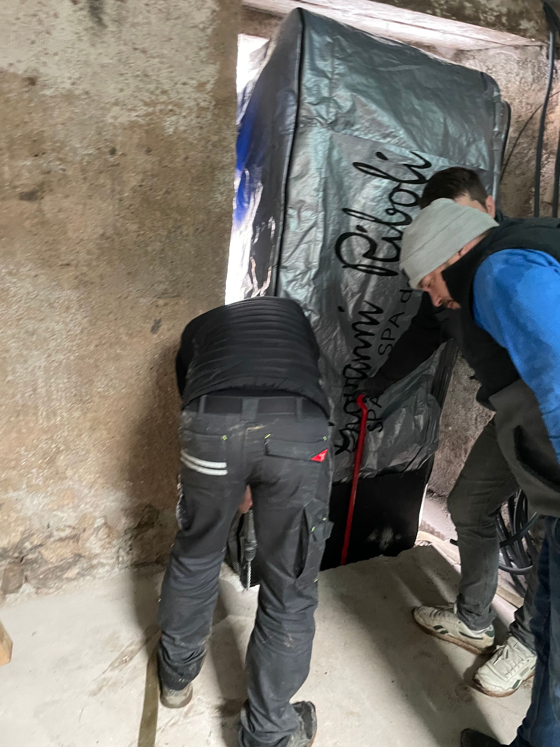 Deux hommes se tiennent l'un à côté de l'autre dans une pièce et regardent quelque chose.