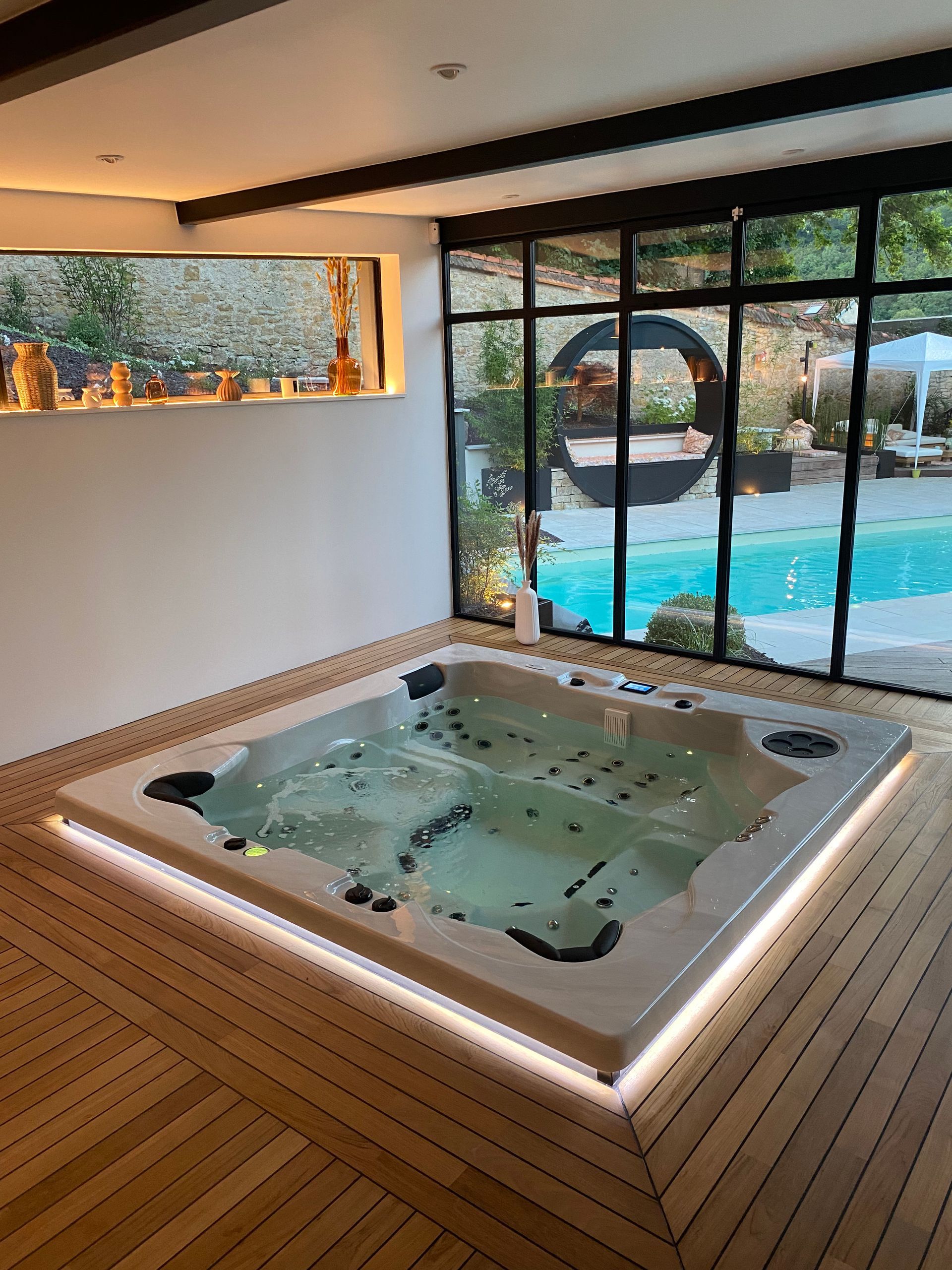 Un grand bain à remous se trouve dans une pièce à côté d'une piscine.