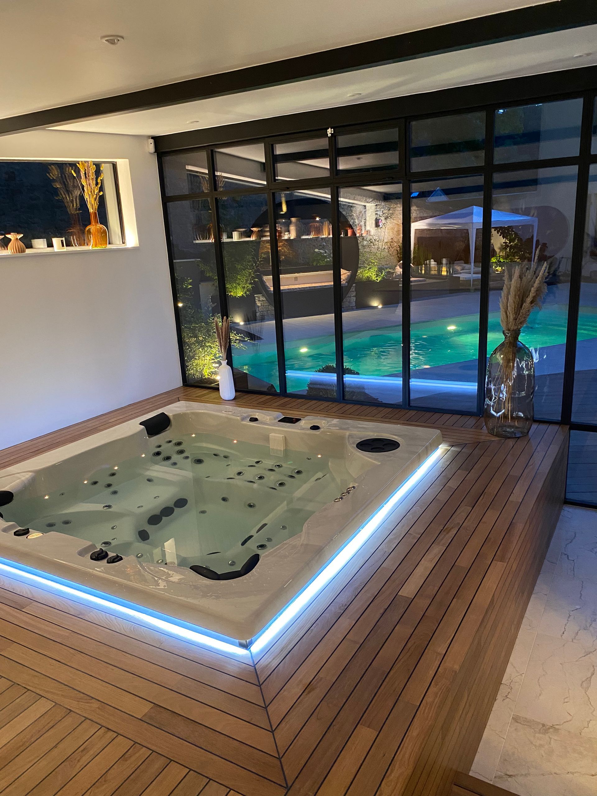 Un grand jacuzzi se trouve dans une pièce à côté d'une piscine.