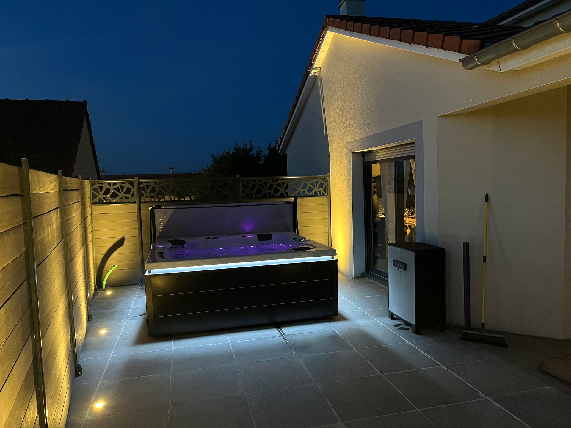 Un jacuzzi est éclairé la nuit devant une maison