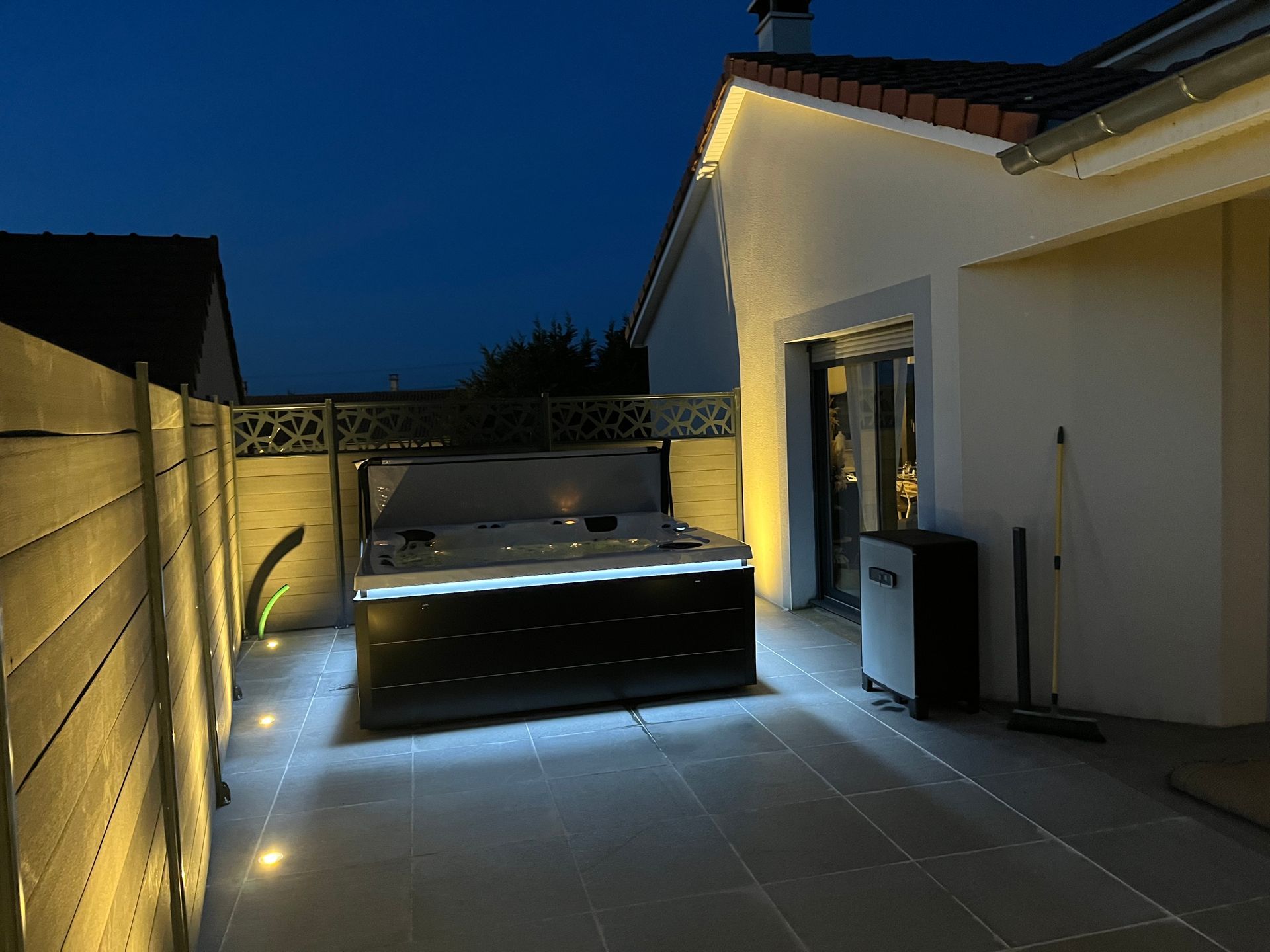 Un jacuzzi est éclairé à l'extérieur d'une maison la nuit
