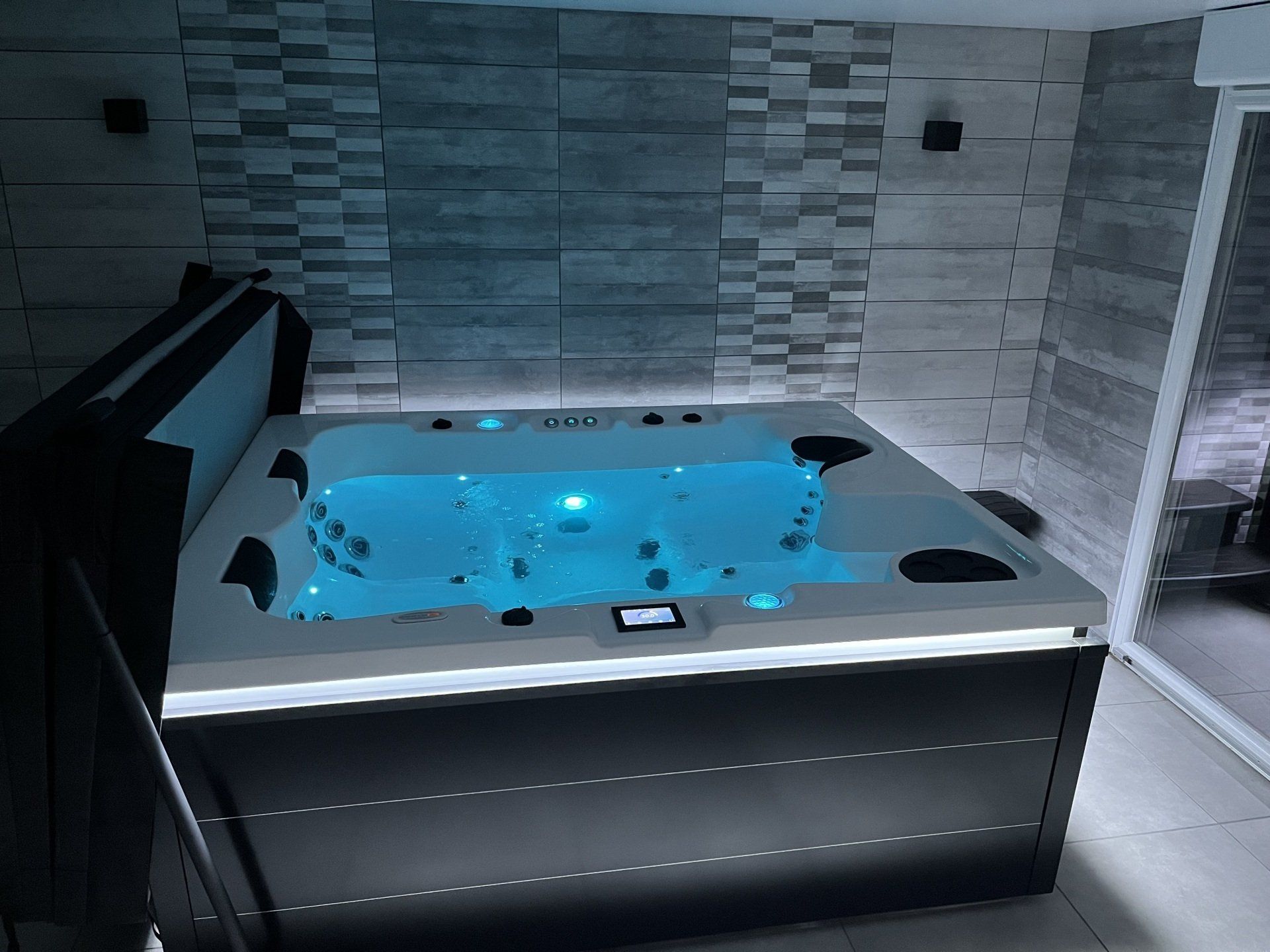 Un jacuzzi noir et blanc avec de l'eau bleue dans une salle de bain
