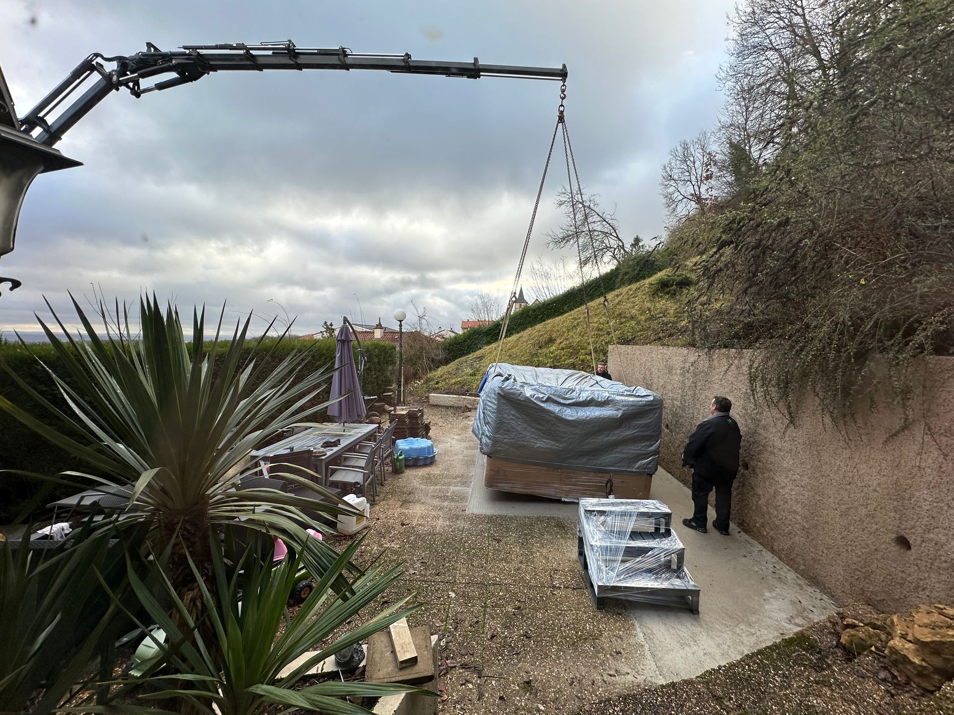 Un homme se tient à côté d'une grue dans une cour arrière.