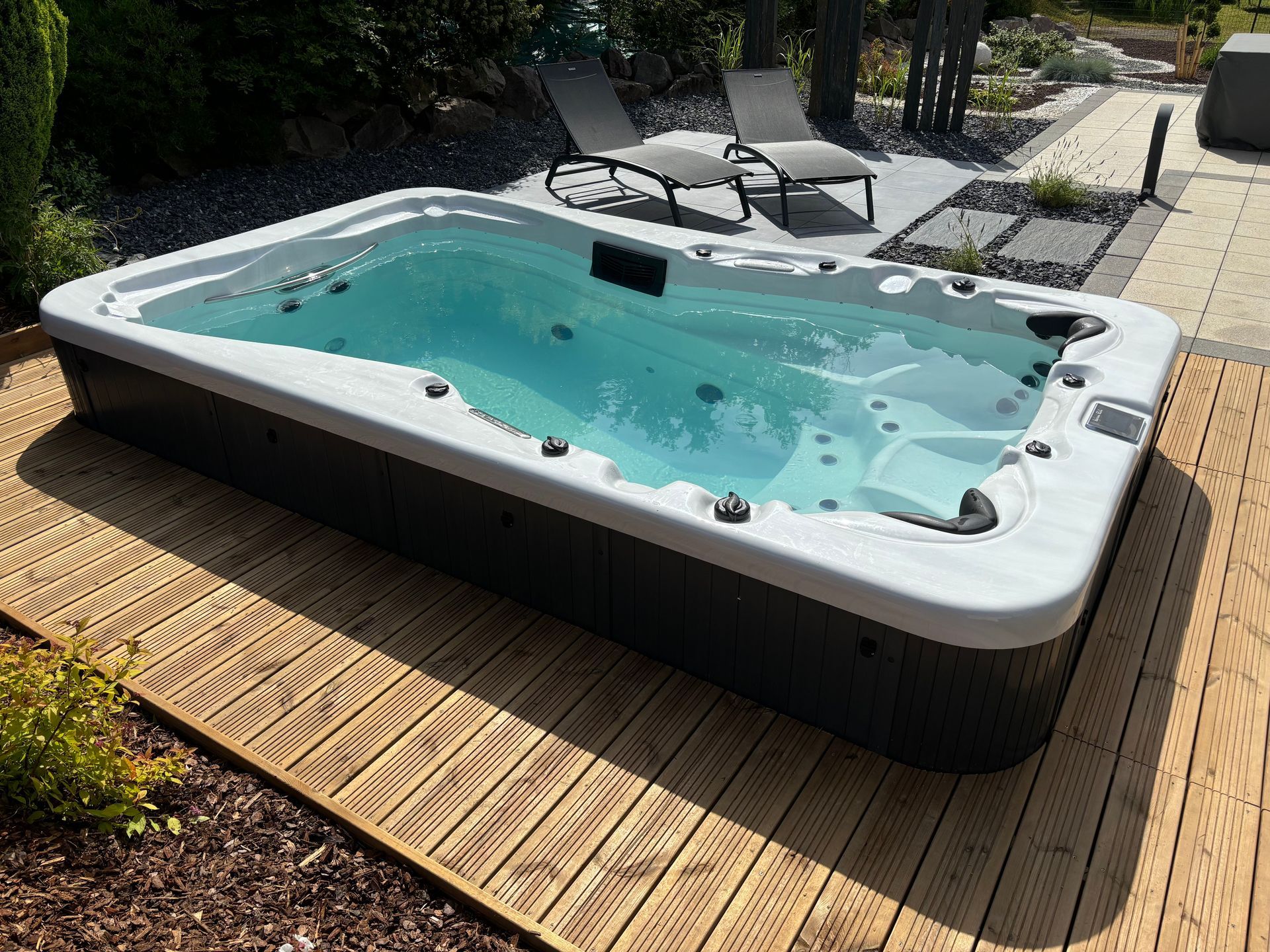 Un grand bain à remous est posé sur une terrasse en bois.