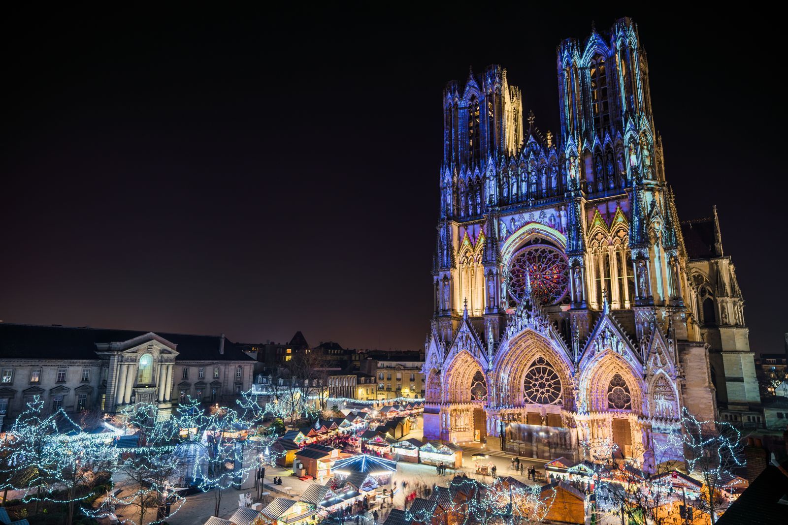 Une grande cathédrale est illuminée la nuit avec des lumières de Noël.