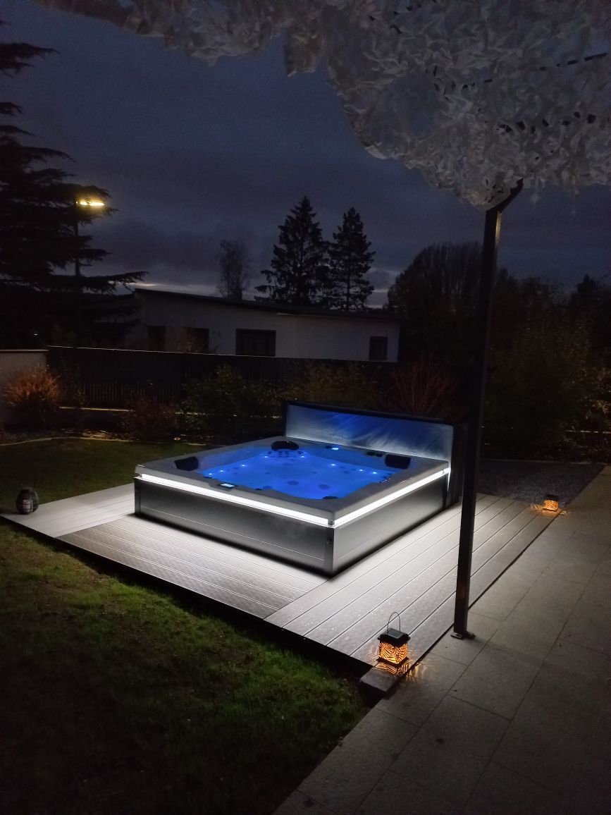 Un jacuzzi est éclairé la nuit dans une cour arrière