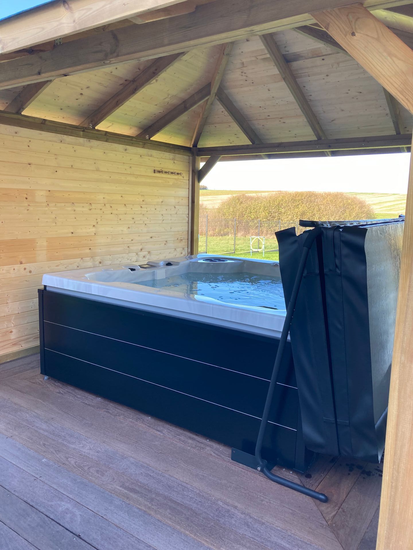 Un bain à remous est installé sous un gazebo en bois.