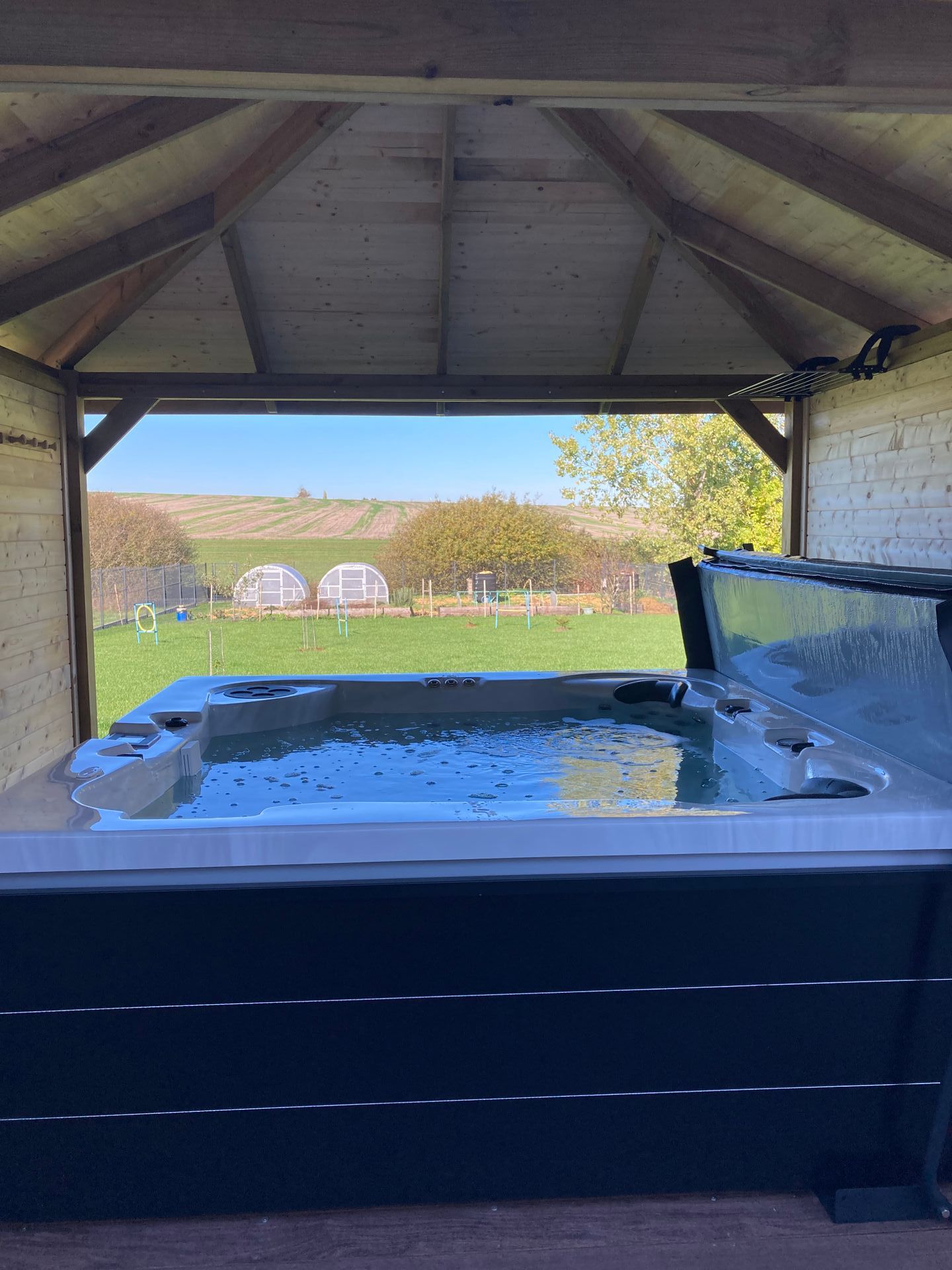 Un bain à remous est placé sous un gazebo avec la porte ouverte.