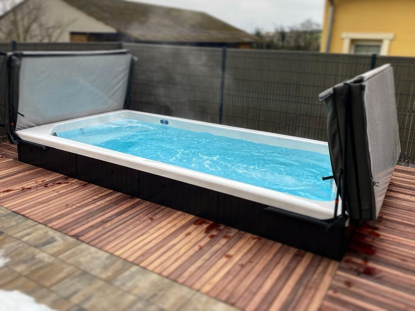 Une grande piscine est posée sur une terrasse en bois.