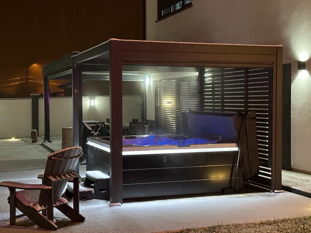 Un jacuzzi est installé sous une pergola dans une cour arrière la nuit.