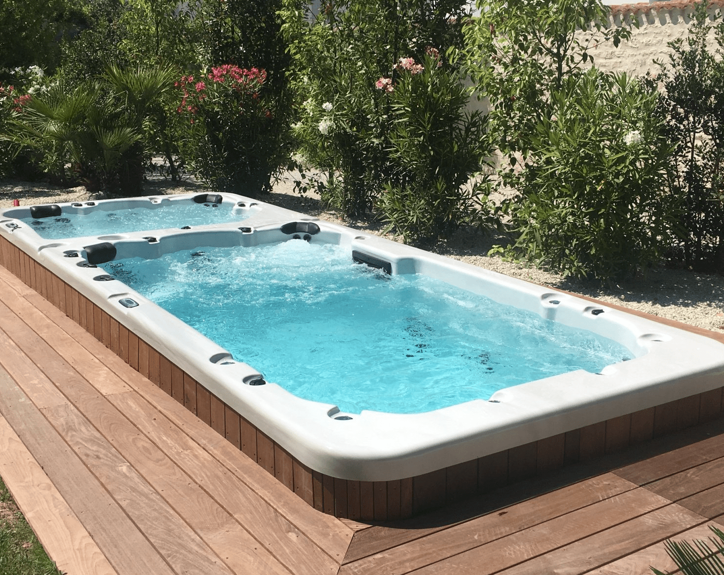 Deux piscines sont situées sur une terrasse en bois entourée d'arbres.