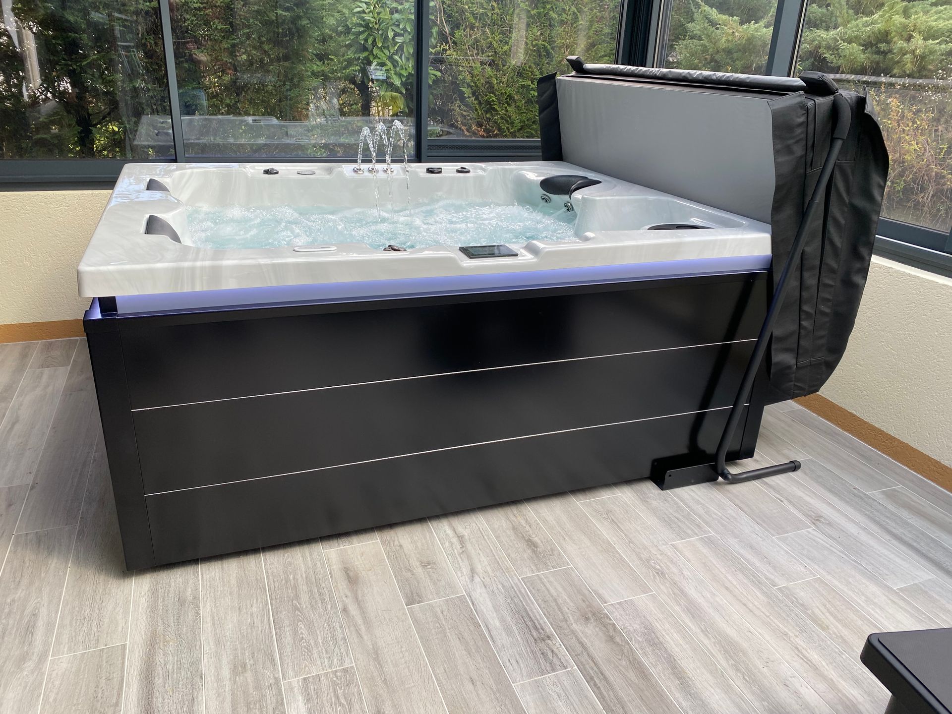 Un grand bain à remous est installé dans une pièce à côté d'une fenêtre.