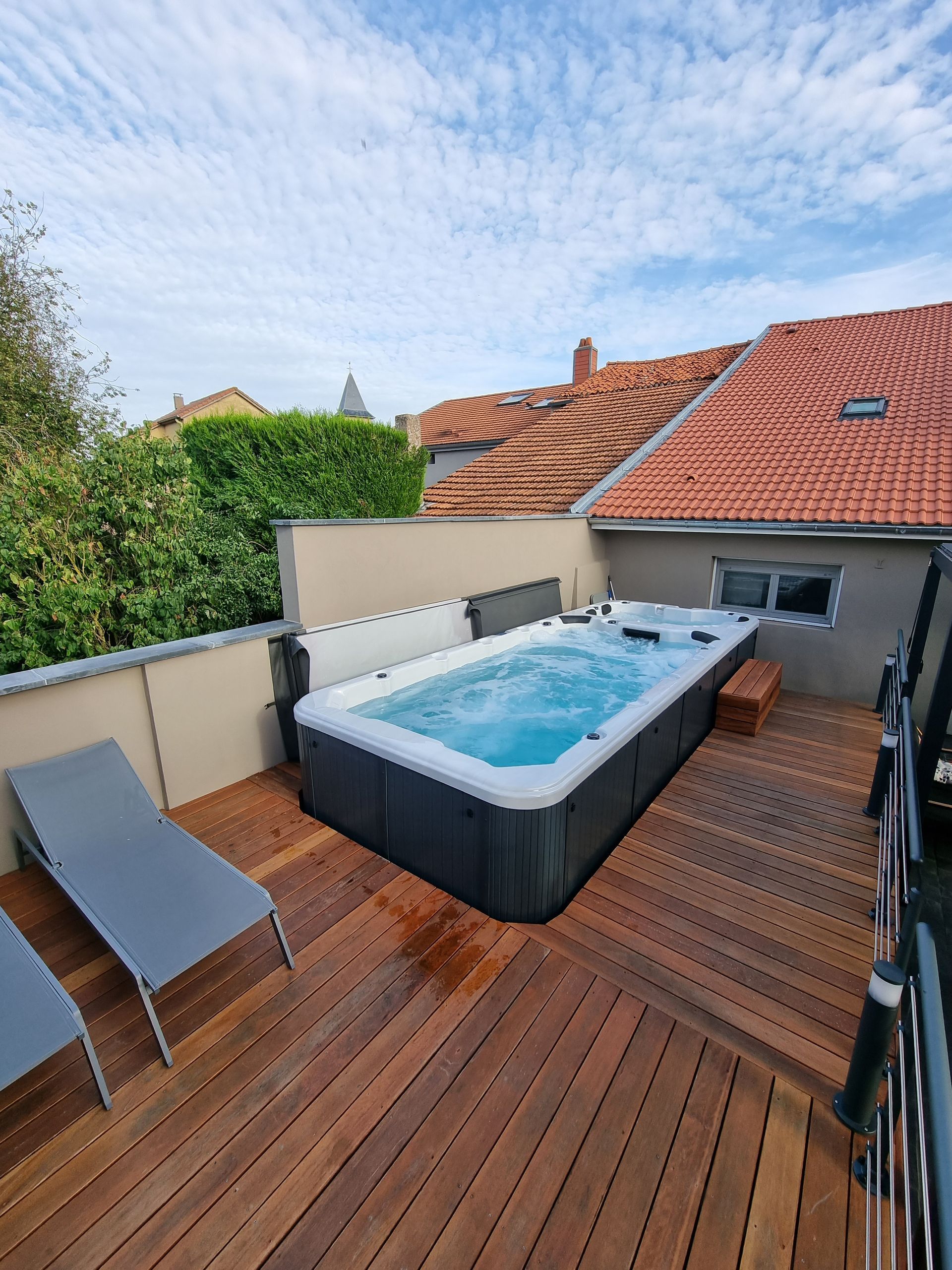 Un grand bain à remous est posé sur une terrasse en bois.