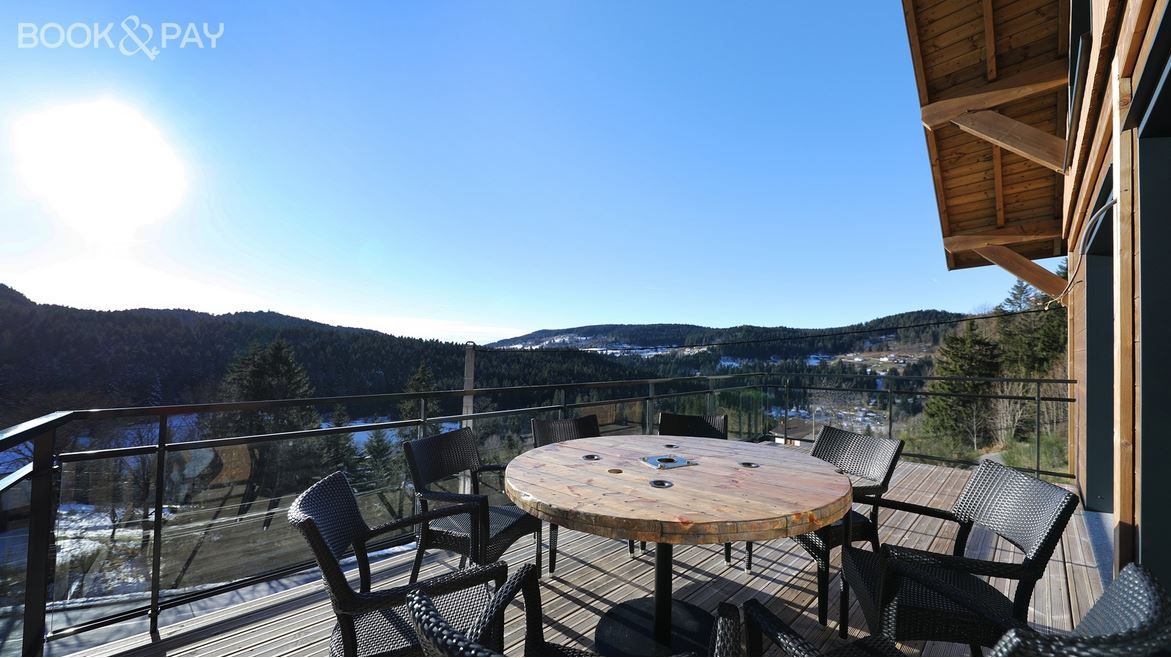 Un balcon avec une table et des chaises donnant sur une chaîne de montagnes