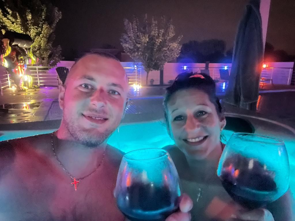 Un homme et une femme tiennent des verres à vin dans un bain à remous.