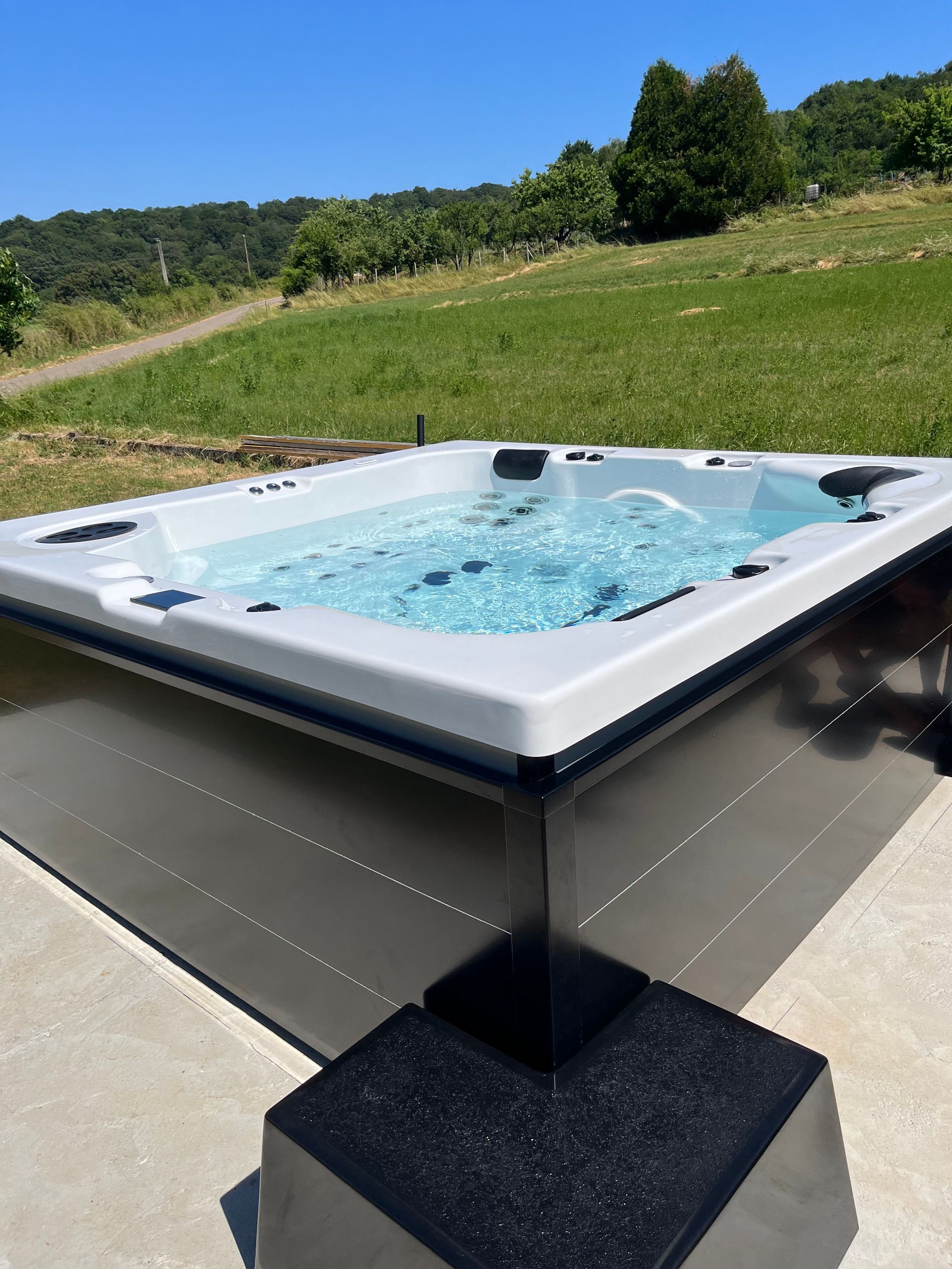 Un bain à remous est posé sur une surface en béton dans un champ.