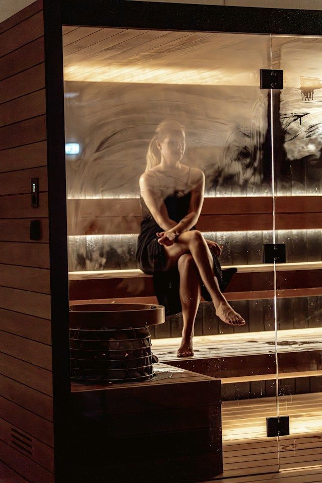 Femme assise dans un sauna, avec de la buée sur la vitre