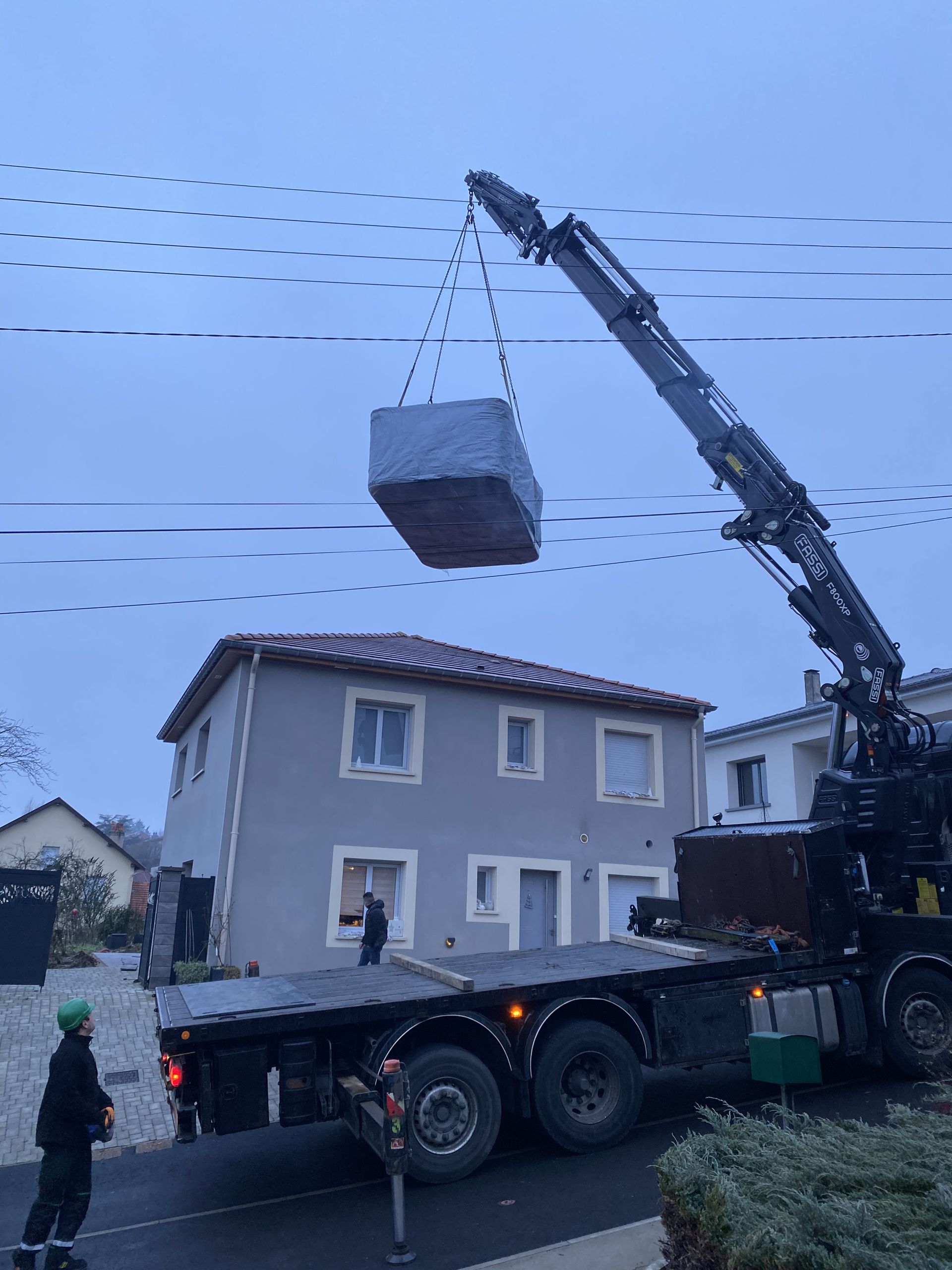 Une grue soulève un gros morceau de béton dans une maison.