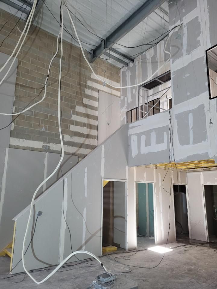 Un bâtiment en construction avec un escalier et beaucoup de fils suspendus au plafond.