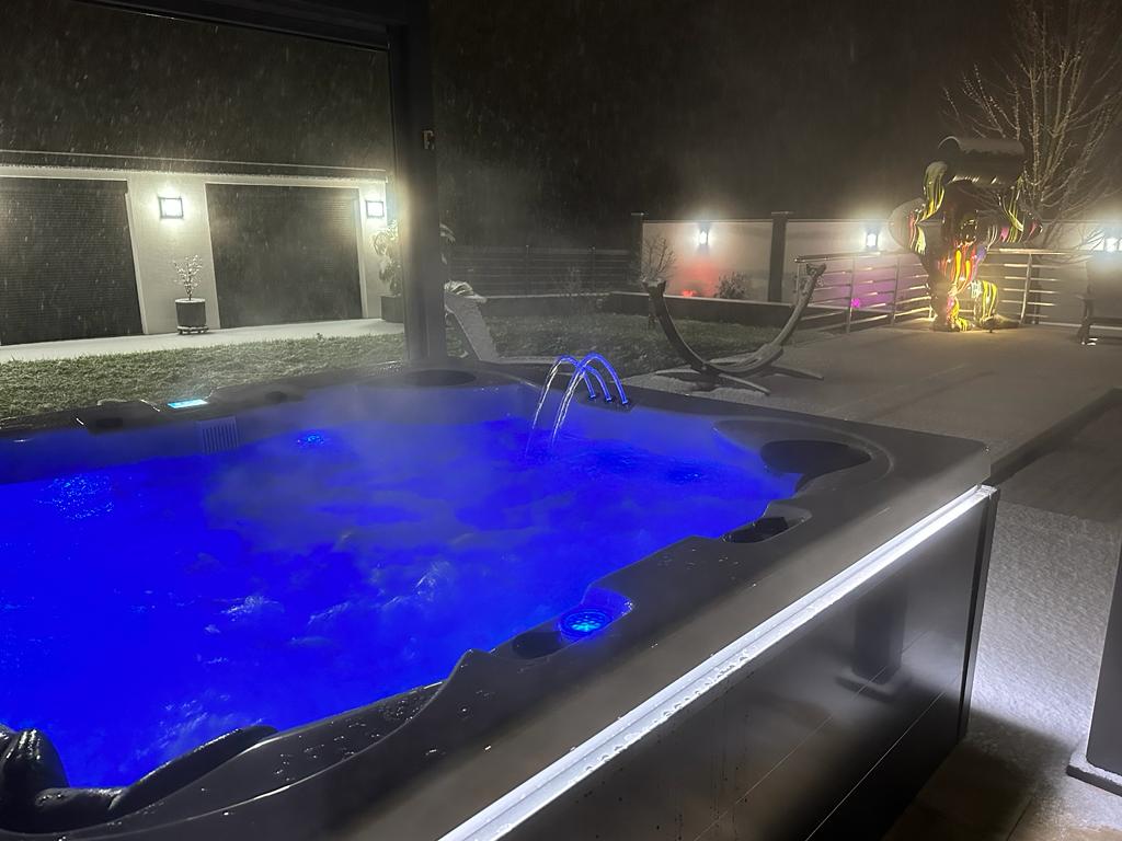 Un bain à remous est éclairé la nuit avec des lumières bleues.