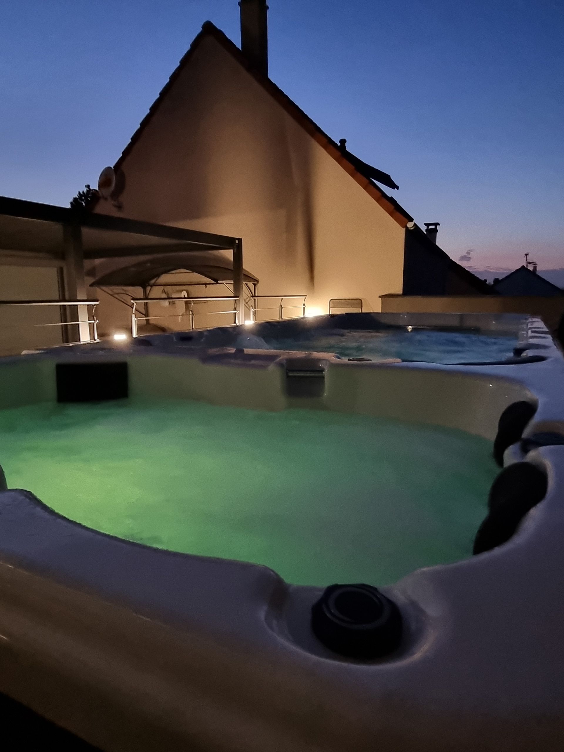 Un jacuzzi est éclairé la nuit devant une maison