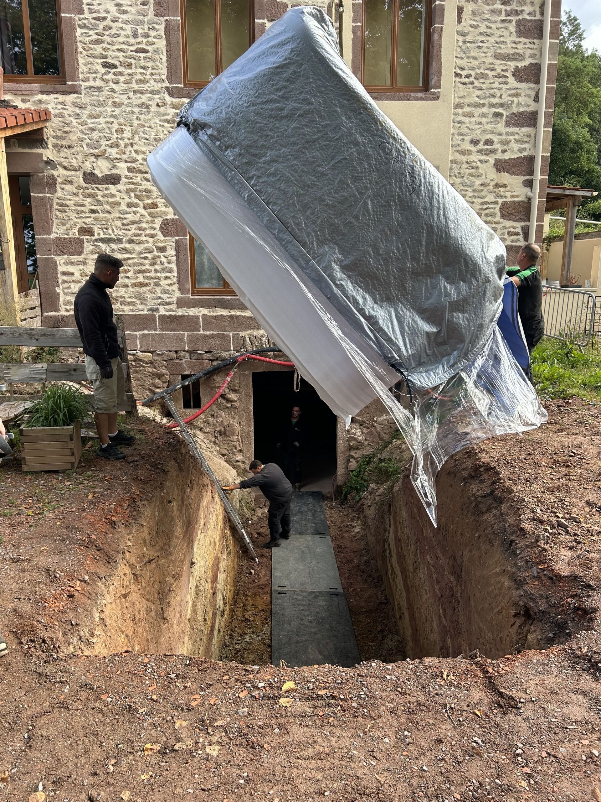 Un homme creuse un trou dans le sol pour installer un jacuzzi.