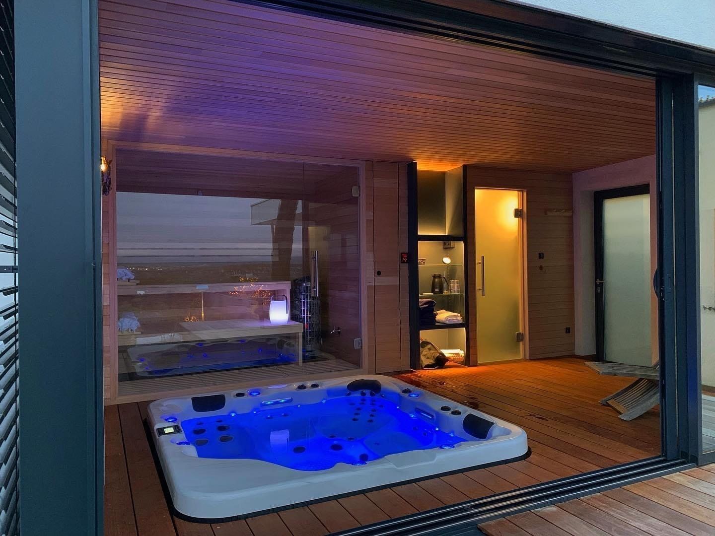 Un bain à remous est installé sur une terrasse en bois à côté d'un sauna.