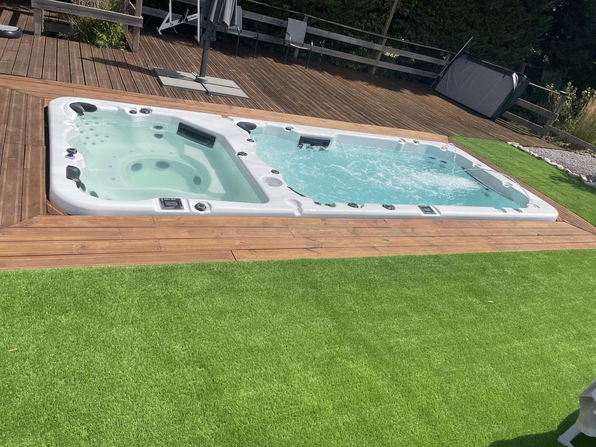 Un bain à remous est posé sur une terrasse en bois dans une cour arrière.
