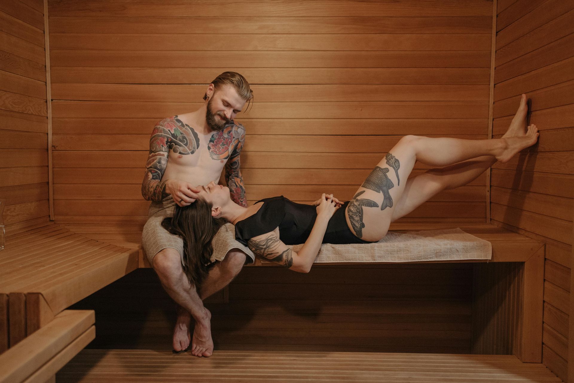 Un homme et une femme sont assis dans un sauna en bois.
