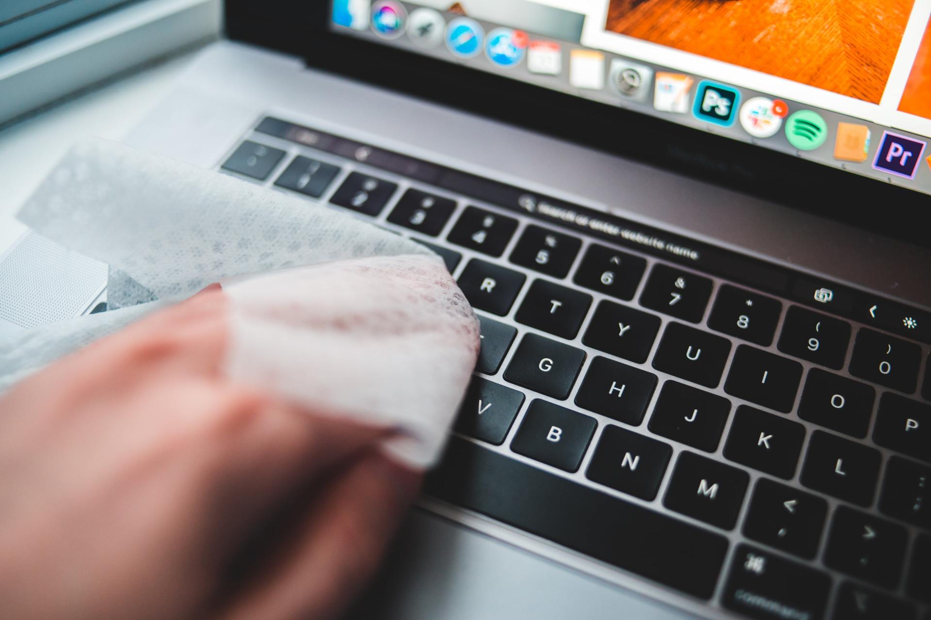 Une personne nettoie le clavier d'un ordinateur portable avec un chiffon.
