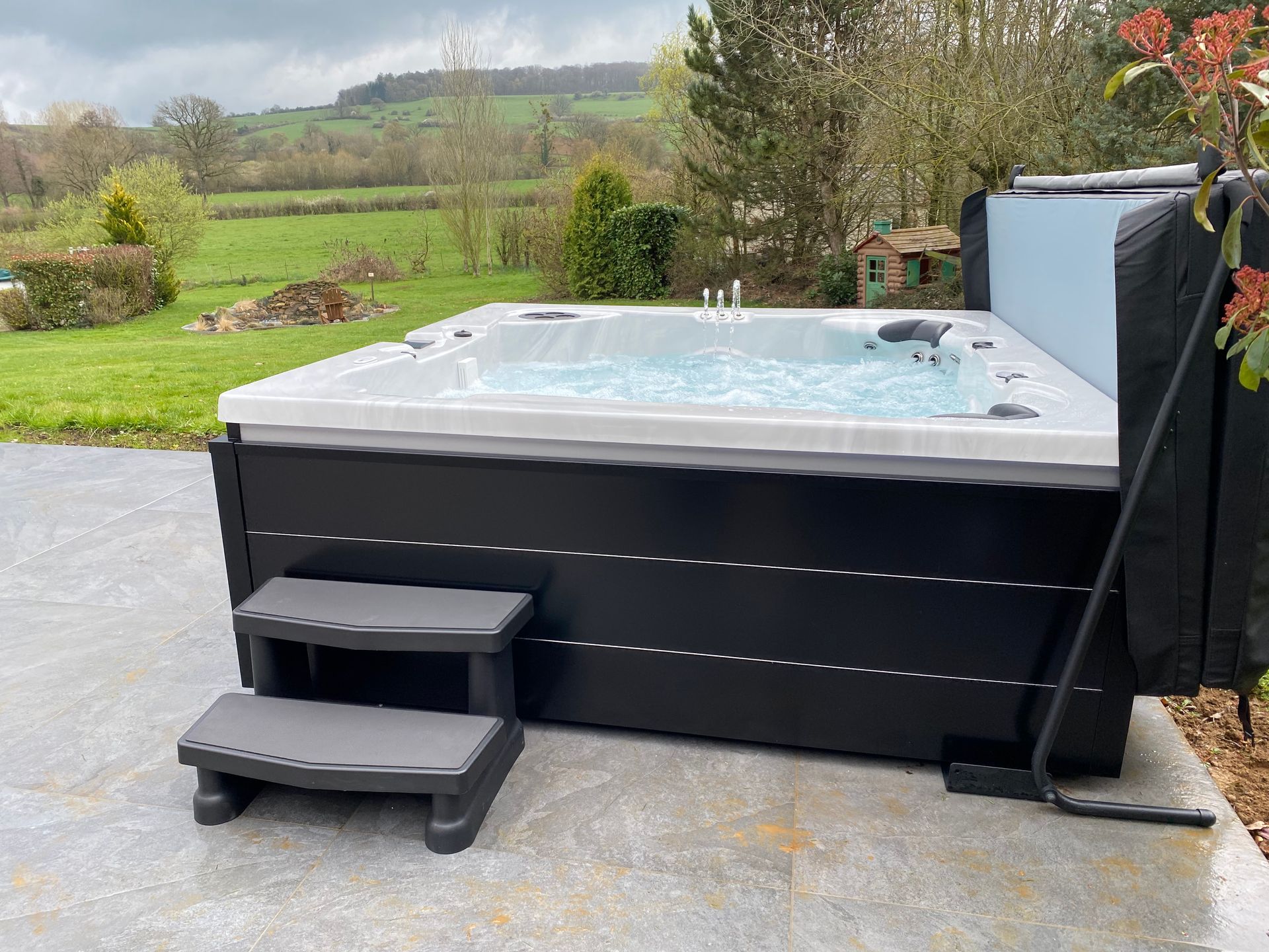 Un bain à remous avec des escaliers menant à celui-ci est assis sur une terrasse en béton.