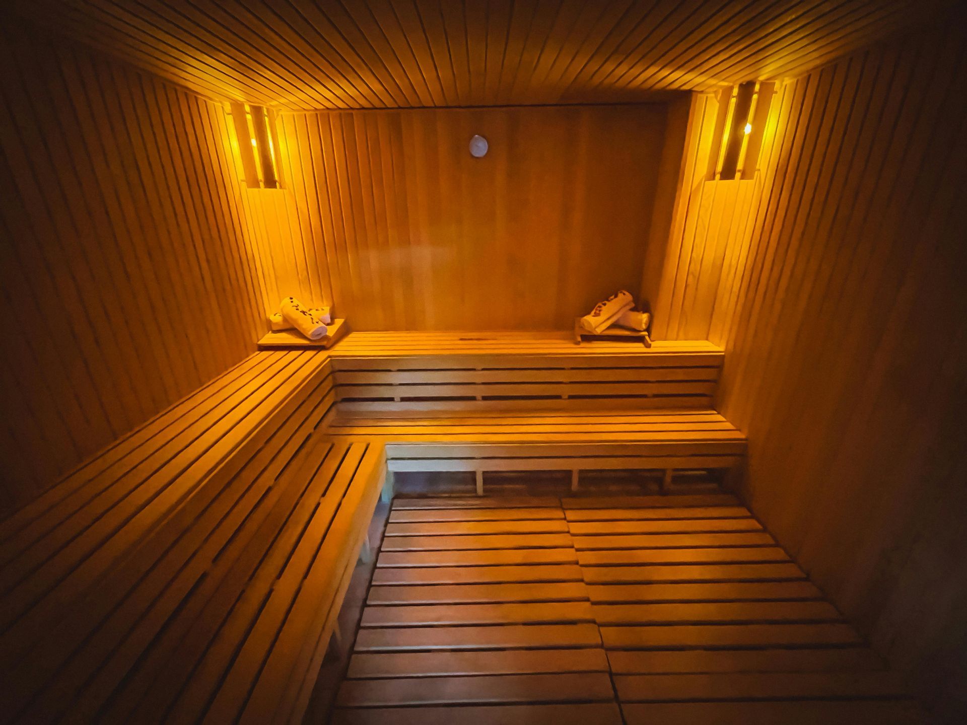 Un sauna en bois avec beaucoup de bancs et de lumières sur les murs.
