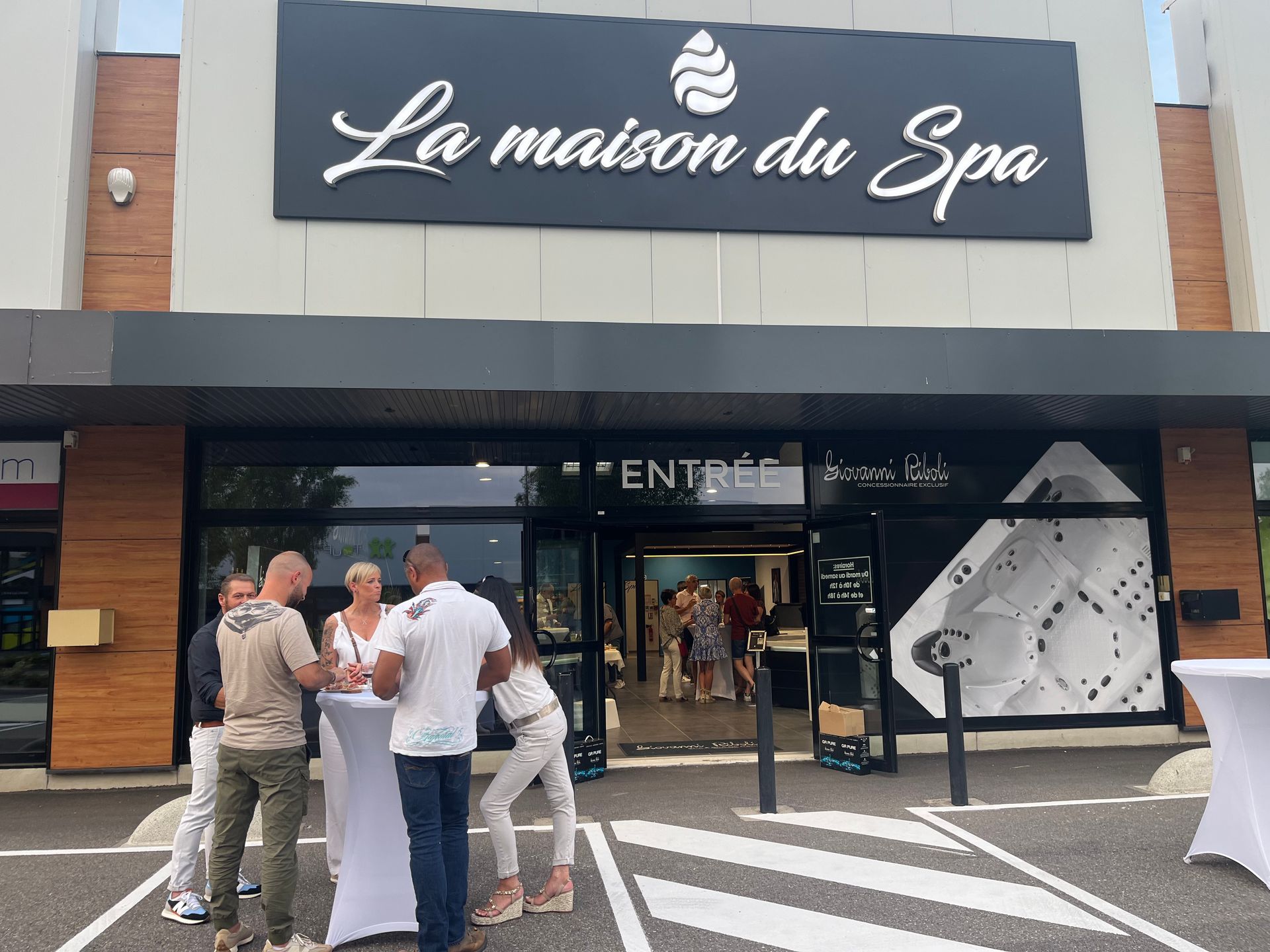 Un groupe de personnes se tient devant un bâtiment sur lequel est écrit la maison du spa