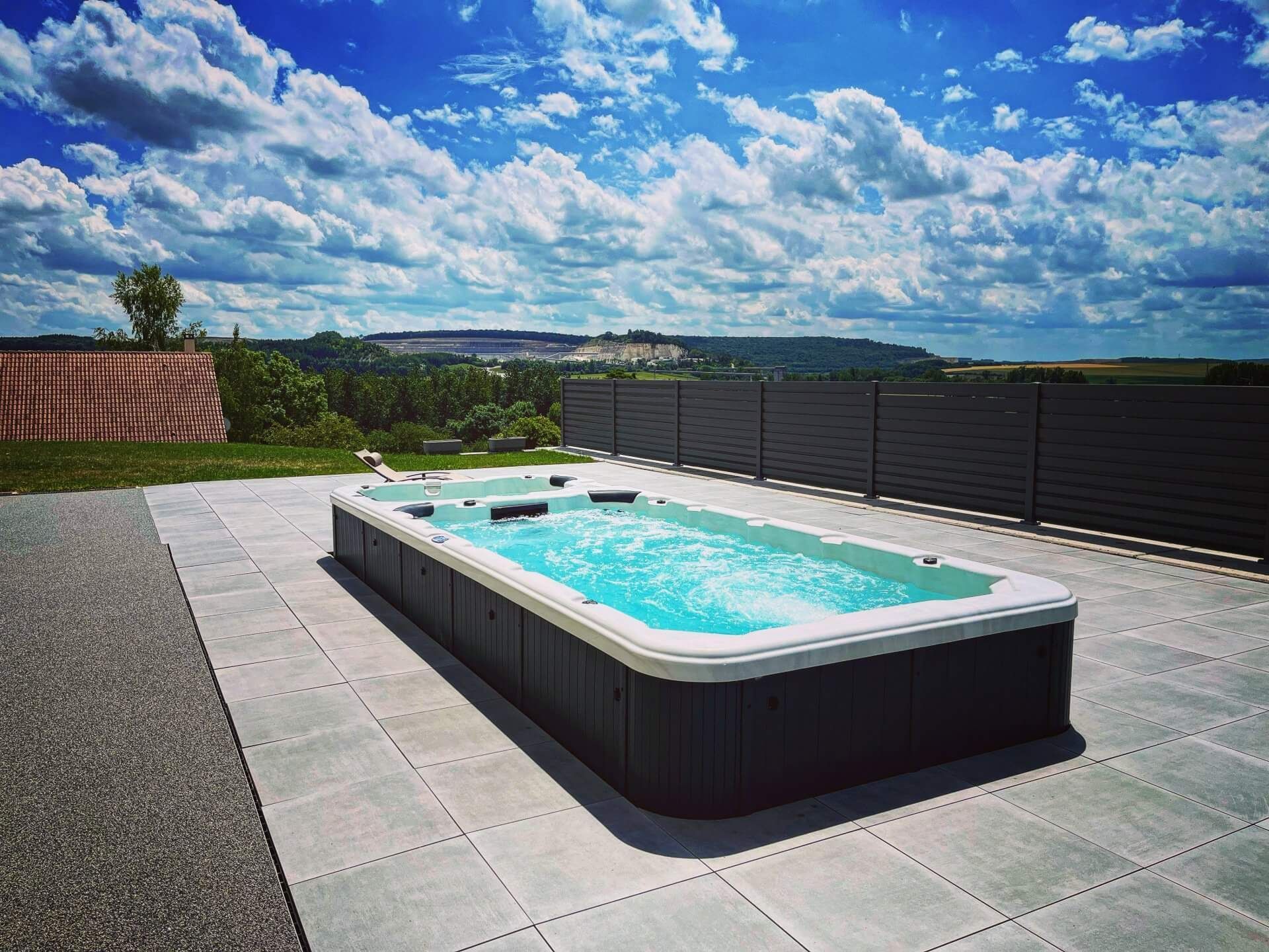 Une grande piscine est située au sommet d'un patio carrelé.