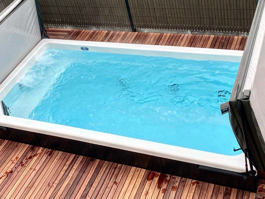 Une petite piscine est posée sur une terrasse en bois.