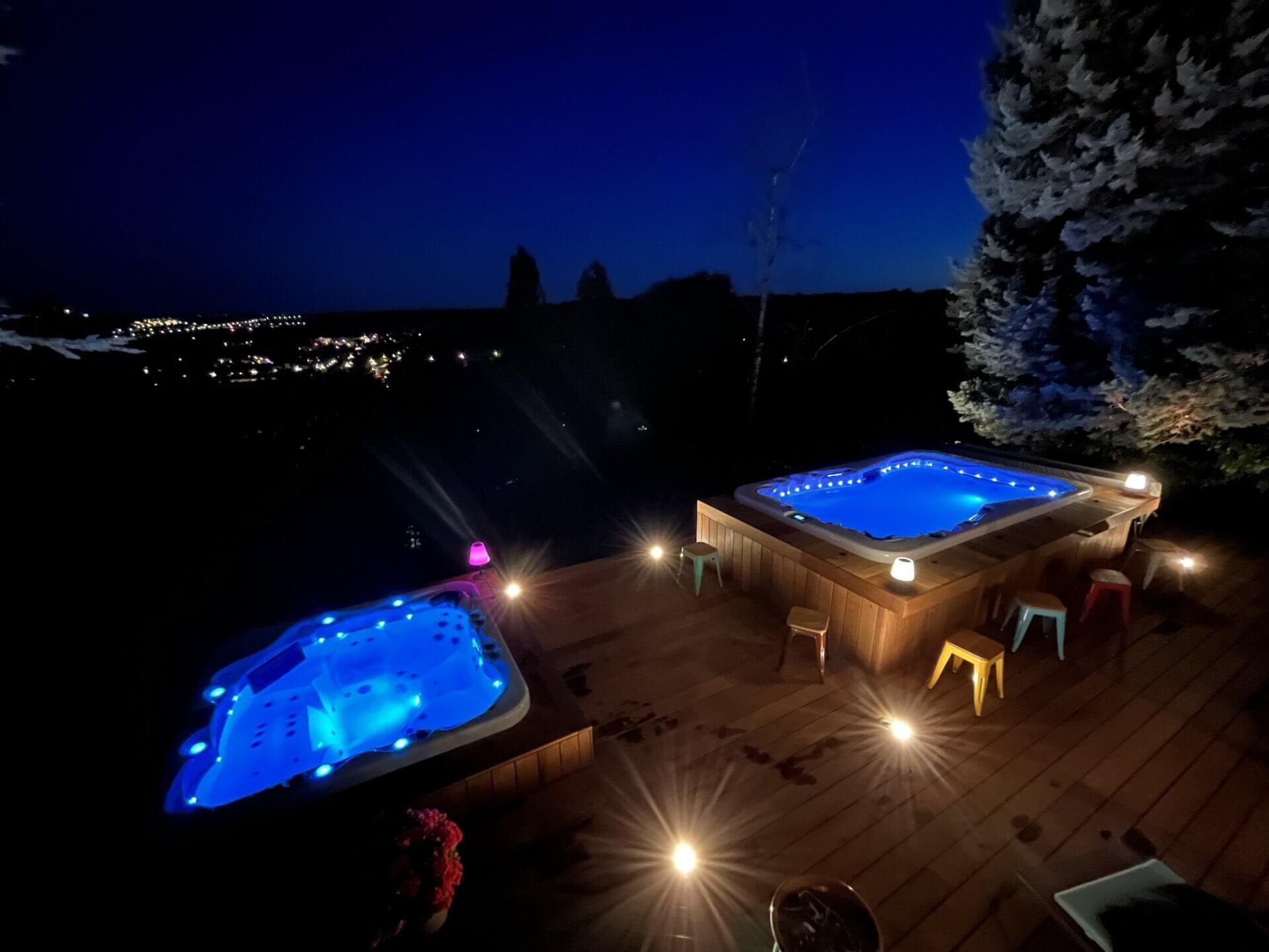 Deux jacuzzis sont éclairés la nuit sur une terrasse