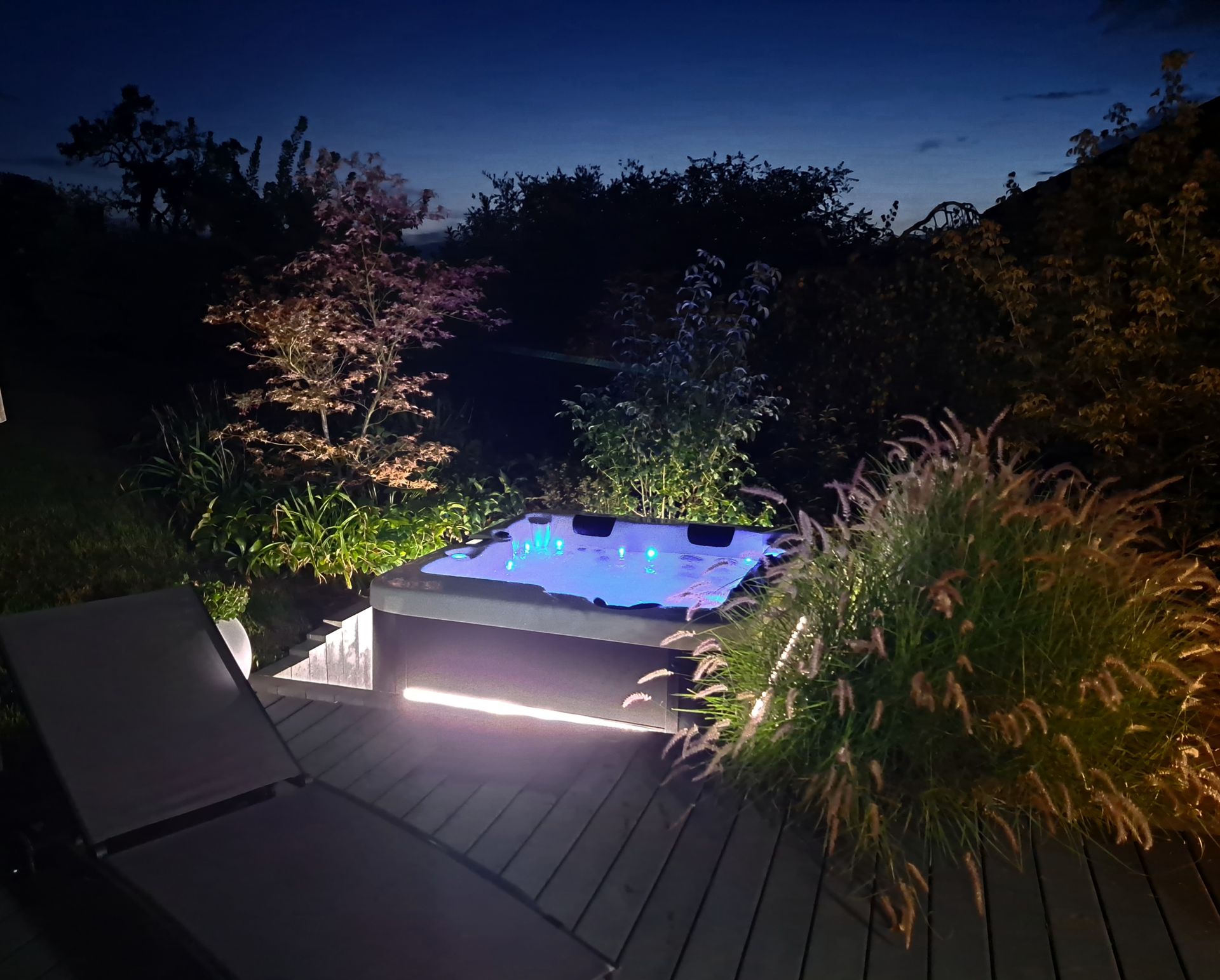 Un jacuzzi est éclairé la nuit sur une terrasse
