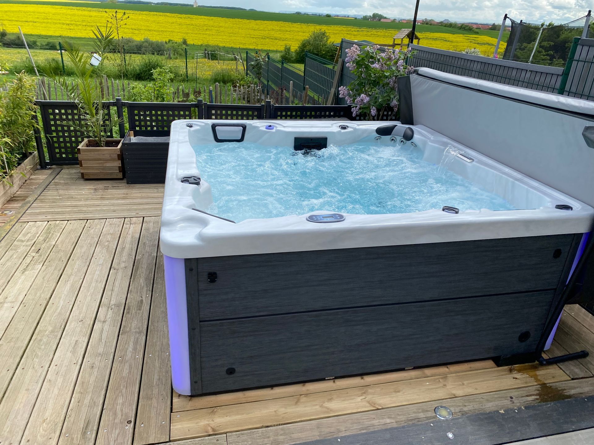 Un grand bain à remous est posé sur une terrasse en bois.