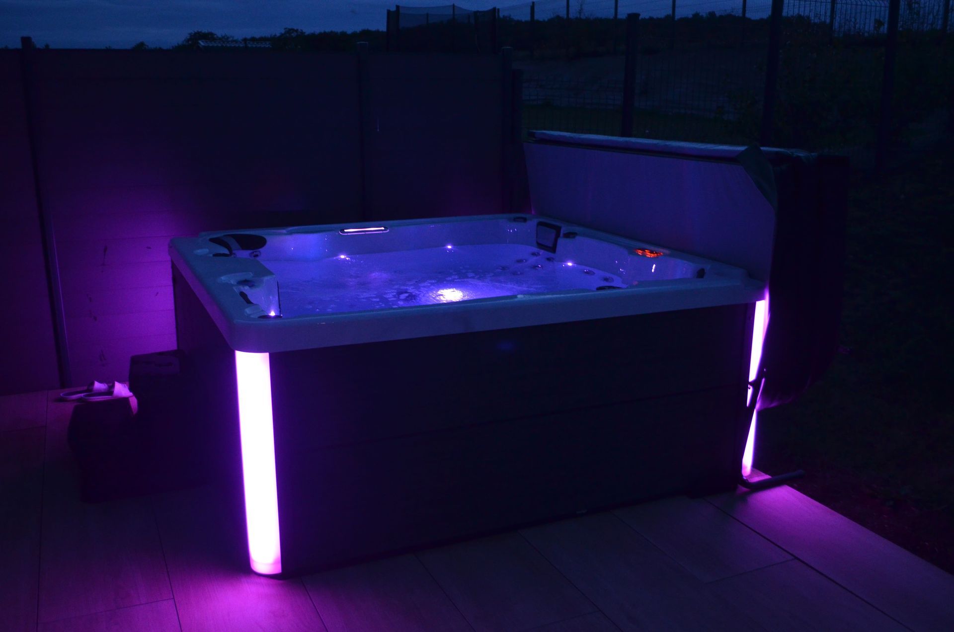 Un bain à remous est éclairé par des lumières violettes la nuit.
