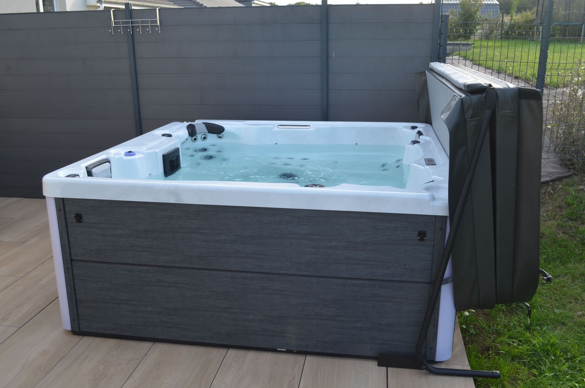 Un bain à remous est installé sur une terrasse à côté d'une clôture.