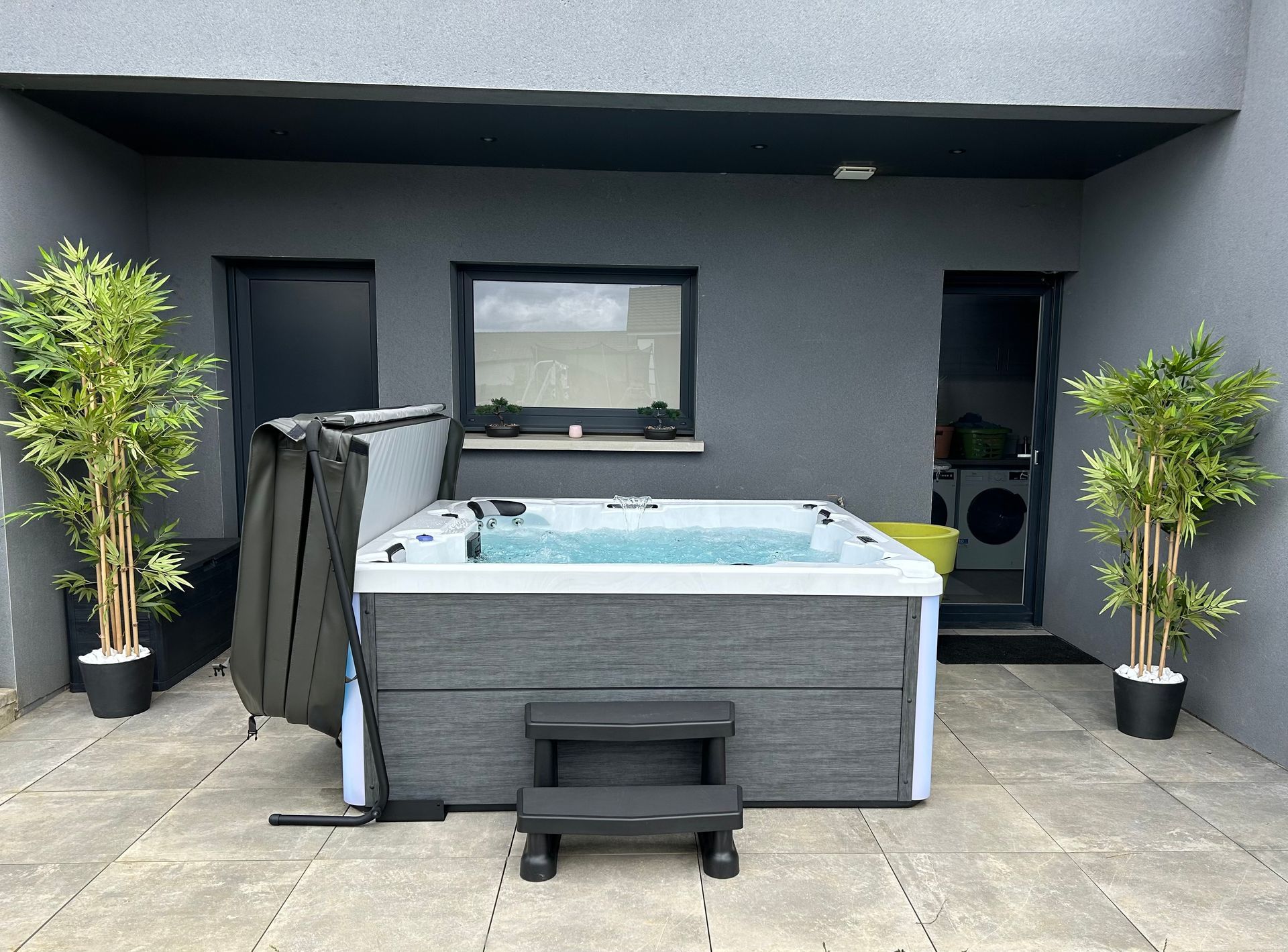Un bain à remous est installé sur une terrasse devant un bâtiment.