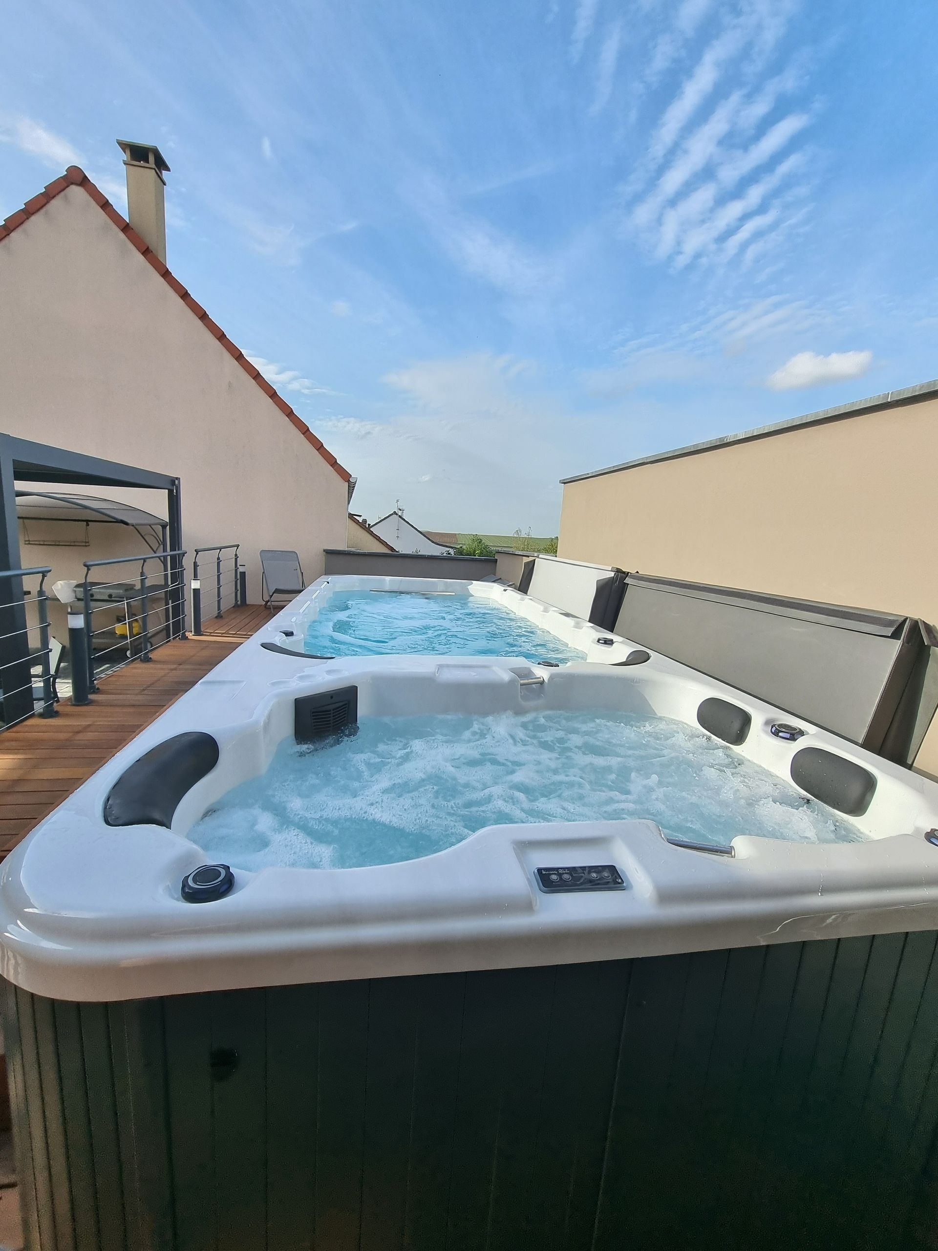 Un grand bain à remous est posé sur une terrasse en bois.