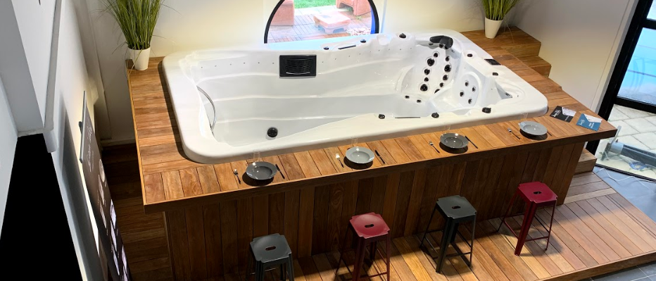 Une grande baignoire jacuzzi blanche est posée sur une plate-forme en bois.