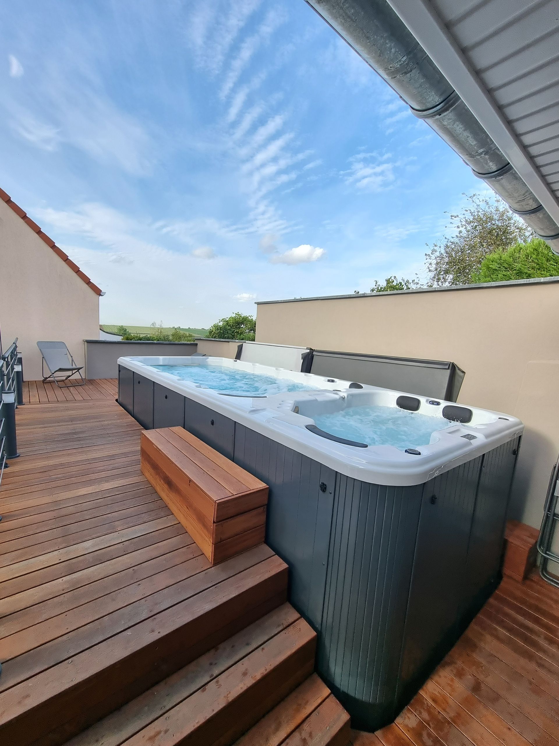 Un grand bain à remous est posé sur une terrasse en bois.